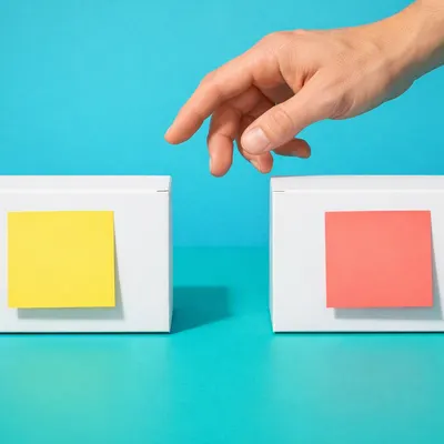 Hand pekar på två vita testkit med en gul och en röd lapp